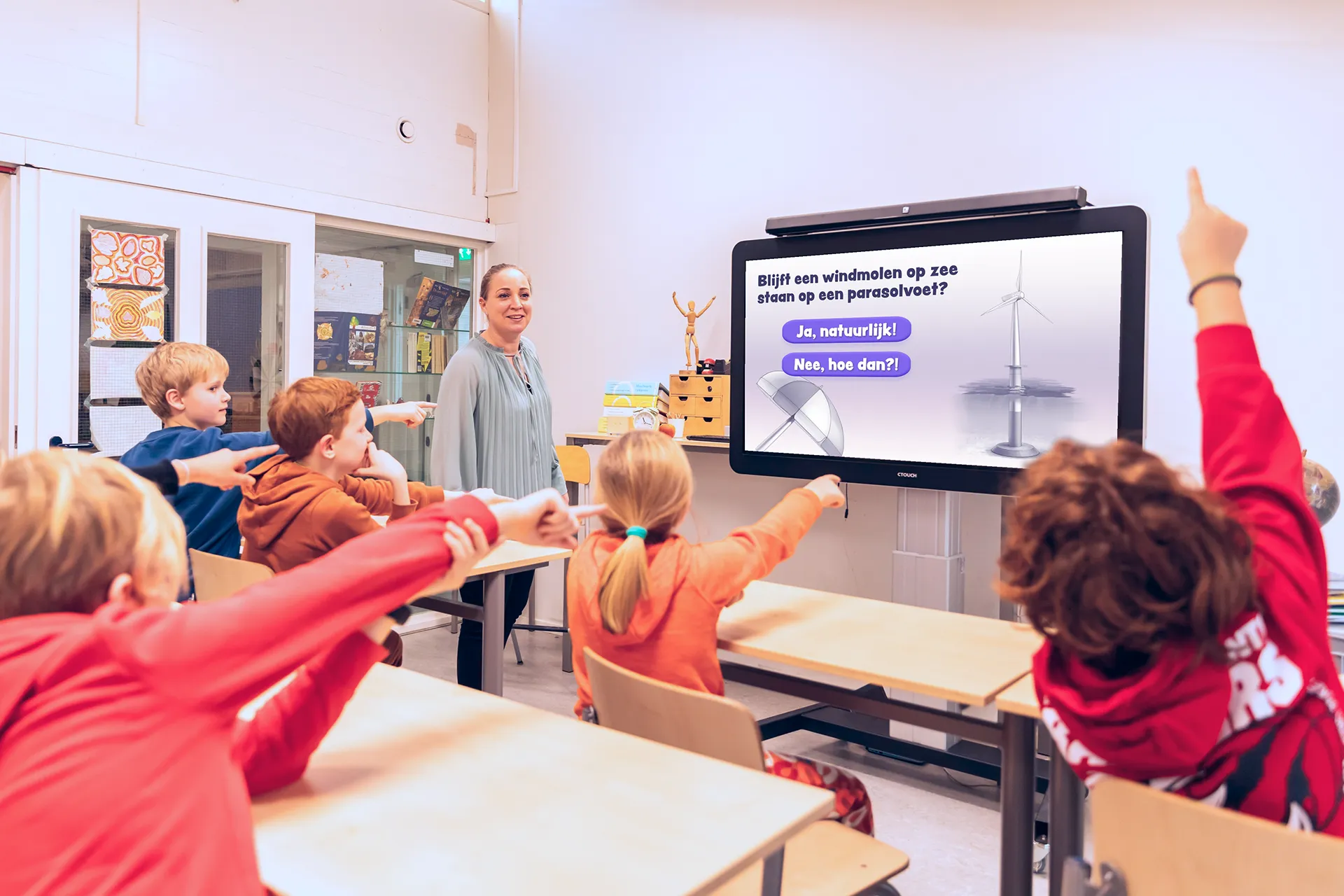 Kinderen in een klaslokaal kijken naar fiedio op een digiboard